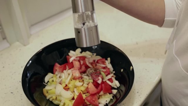 Young beautiful woman preparing a salad in the kitchen. Sprinkle with salt closeup