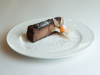 chocolate cheesecake with chocolate glaze on white wood background.