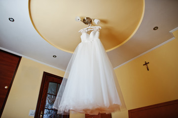 White wedding dress at hangers on the chandelier at ceiling.