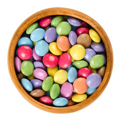 Colorful chocolate candies in wooden bowl. Sugar-coated chocolate confectionery in eight different...