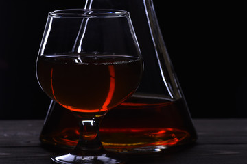 glass and carafe with cognac, whiskey on black wooden table