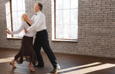 Delighted senior couple enjoying tango at the ballroom