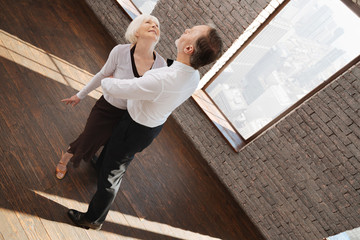Delighted skilled aged couple waltzing in the ballroom