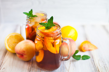 Homemade lemonade with ripe  peaches and fresh mint. Fresh peach ice tea on white wood table. Copy space background.