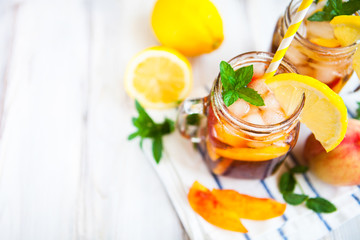 Homemade lemonade with ripe  peaches and fresh mint. Fresh peach ice tea on white wood table. Copy space background.