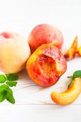 Fototapeta na wymiar Fresh peaches with mint on wooden white background.