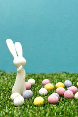A white plastic bunny figurine displayed with speckled easter eggs
