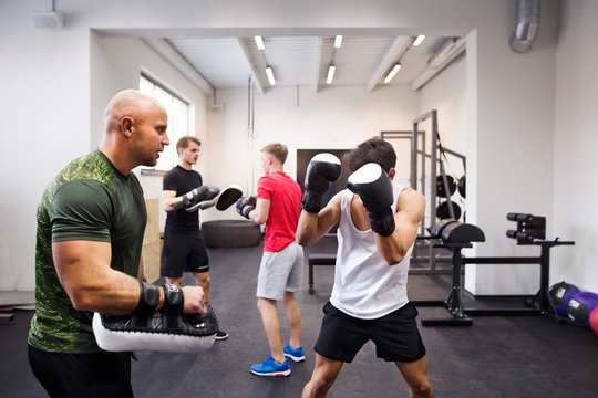 Fit Hispanic Man In Gym Boxing With His Trainer.