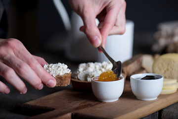 Man's hand putting jam on bread with ricotta cheese