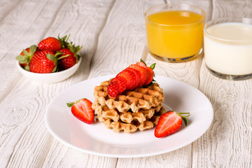 Waffels with strawberry, orange juice and milk