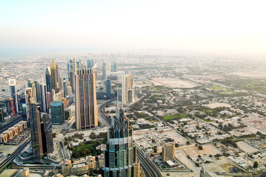 Aerial view of downtown Dubai with buildings skyscrapers and a dusty skyline at sunrise.