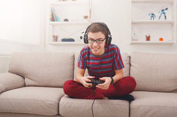 Excited teenage boy playing video game at home