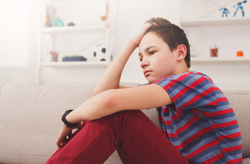 Bored unhappy teenage boy sitting at home © Prostock-studio
