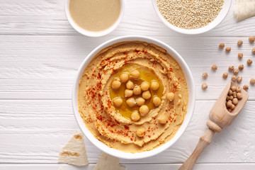 Hummus traditional chickpea vegetarian natural nutrition dip paste with pita paprika sesame tahini parsley and olive oil in clay plate on white table flat lay. Healthy dietary fiber protein food