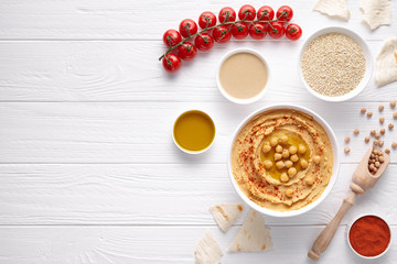 Obraz na płótnie Canvas Hummus homemade arabic healthy vegan dip chickpeas paste snack flat lay with ingridients, tahini, paprika, olive oil, cherrys, pitta bread on white table. Healthy vegetarian nutrition food