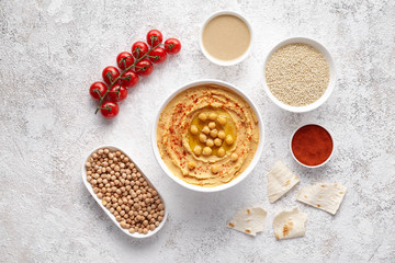 Hummus flat lay with ingridients, healthy diet natural vegetarian snack protein food. Traditional eastern arab appetizer. Sesame, paprika, tahini, pita bread and olive oil on white table background