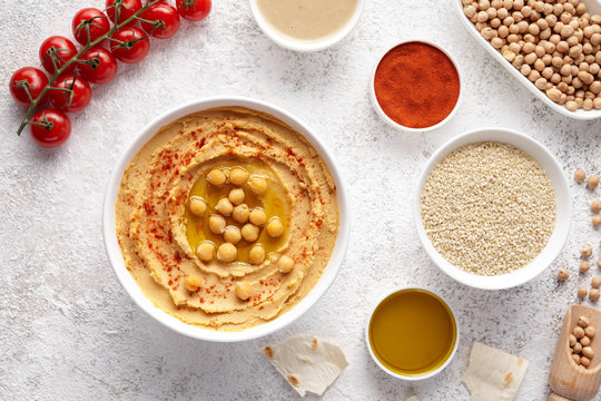 Chickpea hummus flat lay with ingridients, healthy diet natural vegetarian snack protein food. Traditional mediterranean appetizer. Sesame, paprika, tahini, pita bread and olive oil on white table