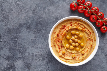 Hummus middle eastern dip paste close up with paprika, tahini, and olive oil, healthy diet natural vegetarian snack protein food. Traditional mediterranean appetizer on blue table