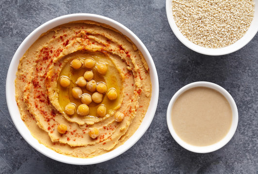 Hummus homemade traditional dip paste flat lay with paprika, tahini, sesame, and olive oil, healthy diet natural vegetarian nutrition snack protein food. Traditional mediterranean appetizer
