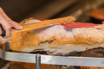 Chef slices serrano ham.