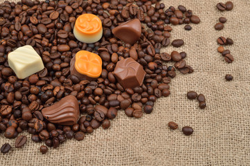 Jute background. Assortment of dark, white and milk chocolate stack on roasted  coffee beans. Sweet and rustic image. Selective macro focus. Chocolates background. Sweets