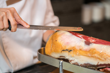 Chef slices serrano ham.