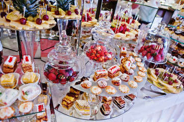 Wedding reception table with different fruits, cakes and sweets.