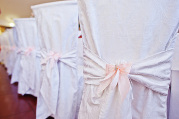 Fototapeta na wymiar Wedding chairs with pink bows on restaurant.