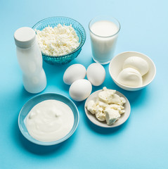Protein products: cheese, cream, milk, eggs on the blue background.