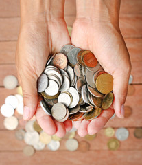 International coins full female hand and copy space on wood plank background