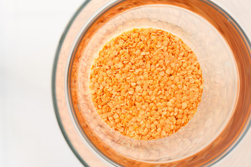 Red lentils in a pottery top view. Background with texture of grains of lentils. Orange bright food background top view.