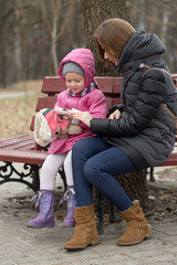 Mom and daughter are sitting on a park bench