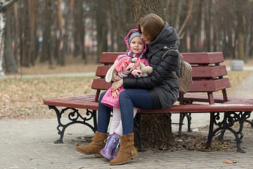 Mom and daughter are sitting on a park bench