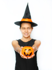 Young woman in witches hat and costume holding Jack pumpkin on a white background. Blur of Halloween Witch focus at Pumpkin.