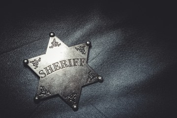 Sheriff badge on gray leather texture background. Macro shot.