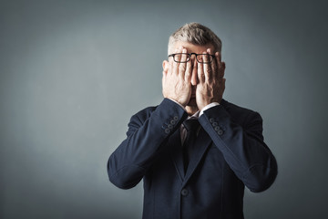 Businessman covering his face with both hands