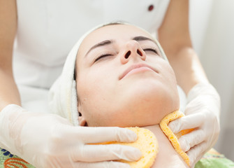 Skin treatment.Beautician at spa makes facial treatment to a beautiful young woman