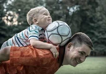 Foto op Canvas Father and son playing football in park at sunny day © Andrii IURLOV