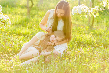 Beautiful mother and daughter in a blooming garden in the spring