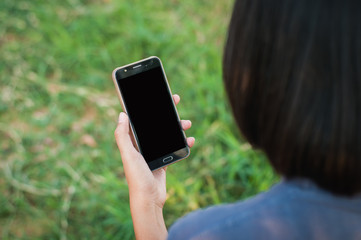 Young woman read and playing smartphone in park,selective focus.