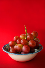 grapes in a bowl on red background