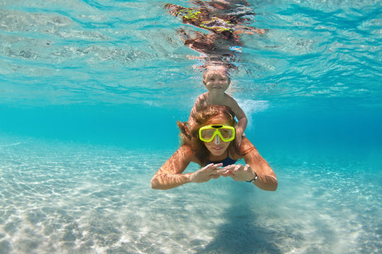 Happy active family - mother, baby son snorkel and dive together underwater in sea pool. Healthy people lifestyle, water sport outdoor adventure, swimming lesson on summer beach vacation with child
