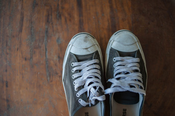 Old worn sneakers on a background of boards