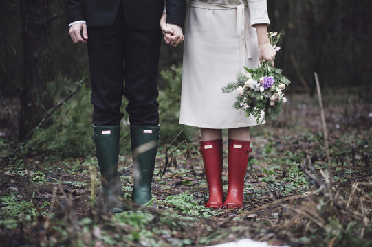 Wedding Couple Standing In The Forest Wearing Colorful Rubber Boots