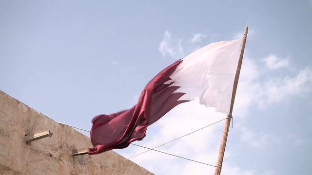 Qatari flag waves in the Souq Waqif standing market in Doha, Qatar.