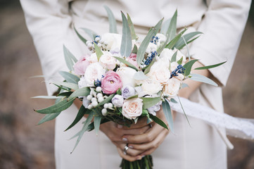 Bride in a white dress holding a beautiful wedding bouquet in her hands