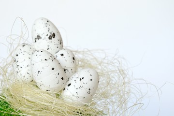 Five white easter eggs made of polystyrene placed on bast nest and green moss ground