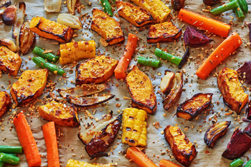 Roasted vegetables (pumpkin, carrot, onion, beetroot, green beans) with spices on a wax paper. 