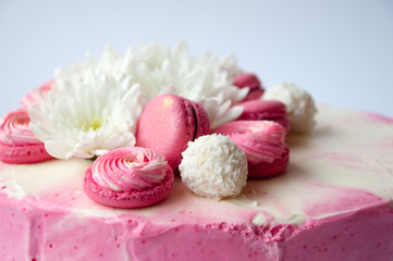 Wedding cake with white spring flowers and macaroon on top. Delicious pink cake isolated on white background.