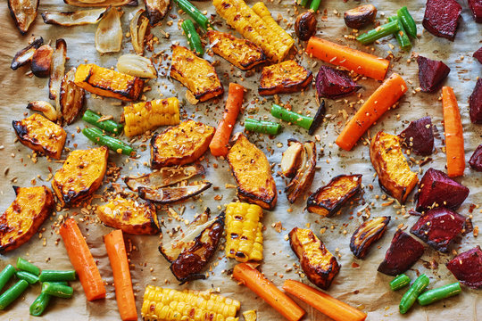 Roasted vegetables (pumpkin, carrot, onion, beetroot, green beans, garlic) with spices on a wax paper. 